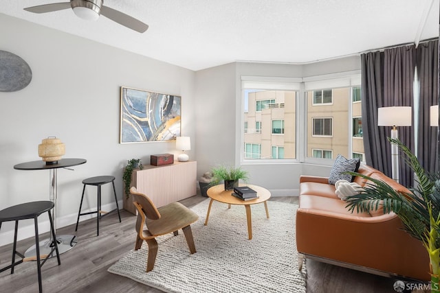 sitting room with ceiling fan, a wealth of natural light, wood finished floors, and baseboards