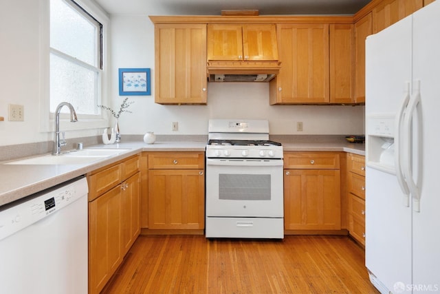 kitchen featuring white appliances, a sink, light countertops, light wood finished floors, and custom range hood