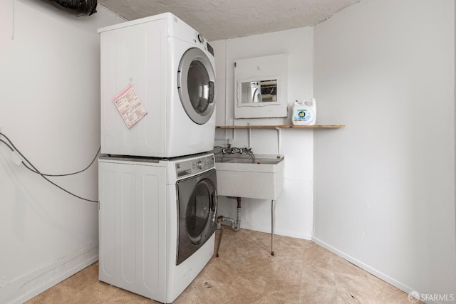 laundry room featuring stacked washer and dryer, baseboards, laundry area, and a textured ceiling