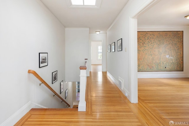 hallway featuring wood finished floors, an upstairs landing, and crown molding