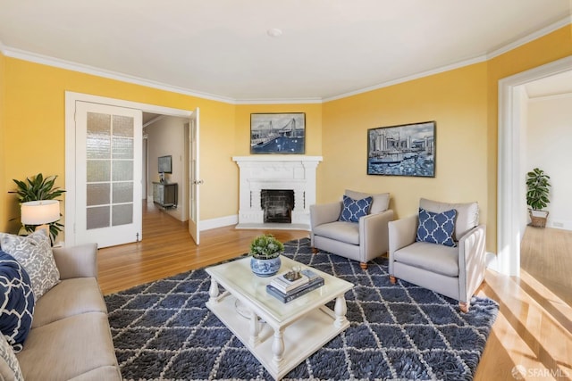 living area featuring baseboards, a fireplace with raised hearth, crown molding, and wood finished floors