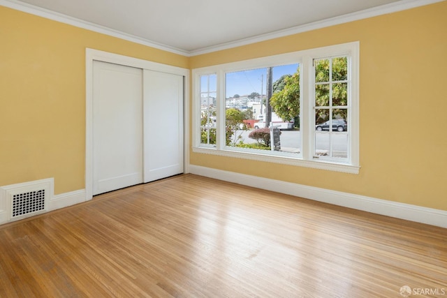 unfurnished bedroom with light wood-style floors, visible vents, ornamental molding, and baseboards