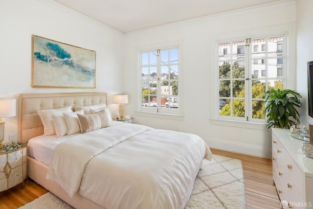 bedroom featuring light wood finished floors, baseboards, and crown molding