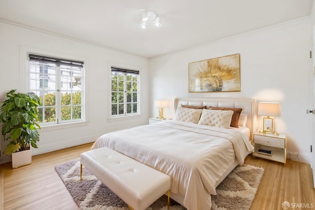 bedroom with ornamental molding, light wood-style floors, and baseboards