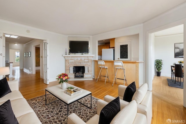 living room with a fireplace with raised hearth, crown molding, baseboards, and wood finished floors