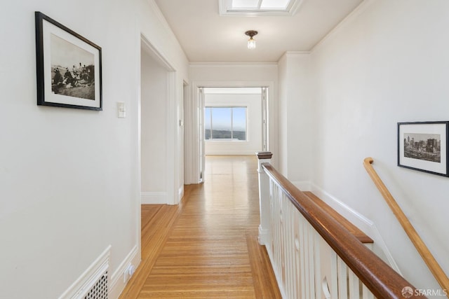 hall featuring light wood-style floors, visible vents, crown molding, and an upstairs landing