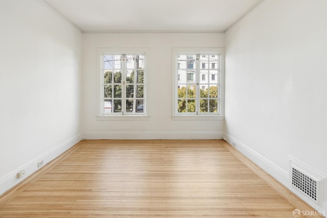 unfurnished room with light wood finished floors, baseboards, visible vents, and crown molding