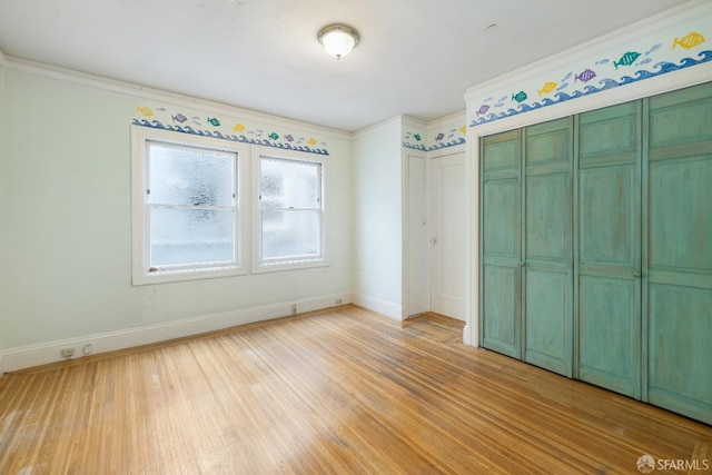 unfurnished bedroom featuring light wood-style flooring, baseboards, and crown molding