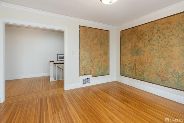 spare room featuring light wood-type flooring, baseboards, visible vents, and ornamental molding