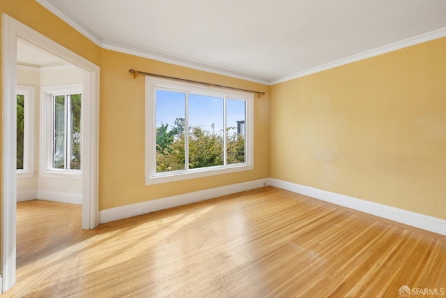 spare room with ornamental molding, light wood-type flooring, and baseboards