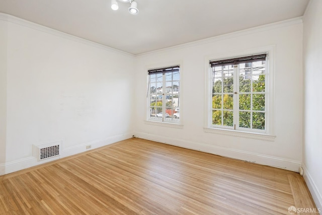 spare room featuring ornamental molding, visible vents, light wood-style floors, and baseboards