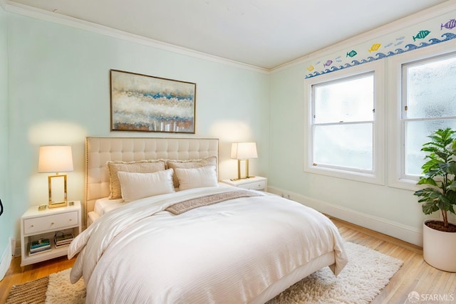 bedroom with baseboards, wood finished floors, and crown molding