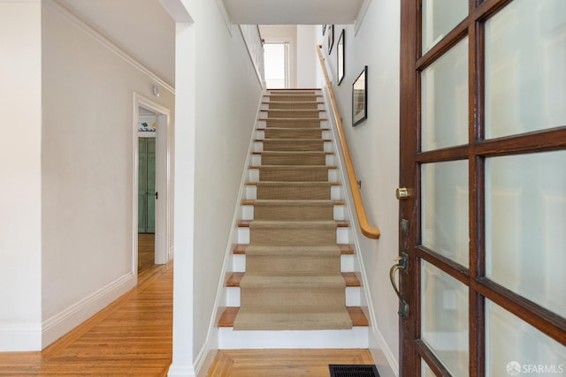 staircase featuring visible vents, baseboards, and wood finished floors