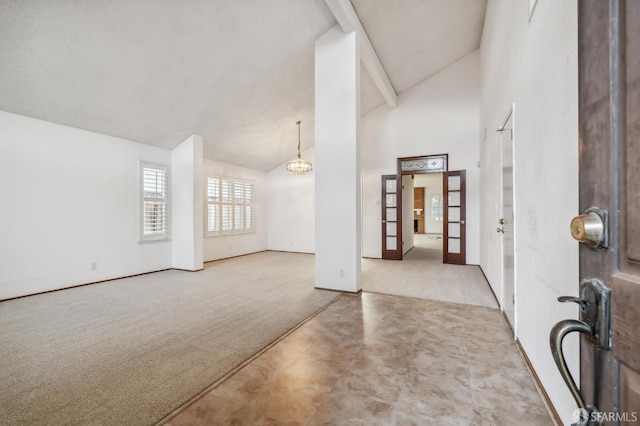 carpeted entrance foyer featuring a notable chandelier and high vaulted ceiling