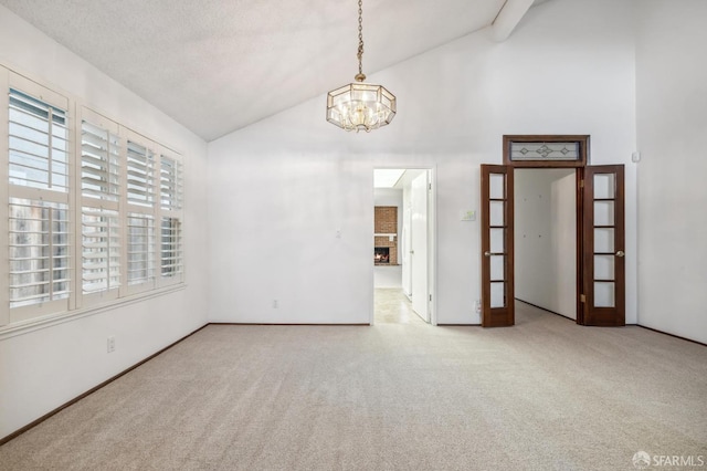 carpeted empty room with high vaulted ceiling, a fireplace, a textured ceiling, beamed ceiling, and a chandelier