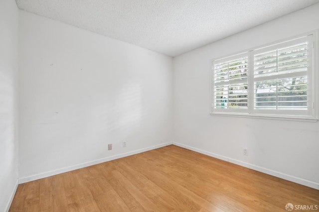 unfurnished room featuring light wood-type flooring, baseboards, and a textured ceiling