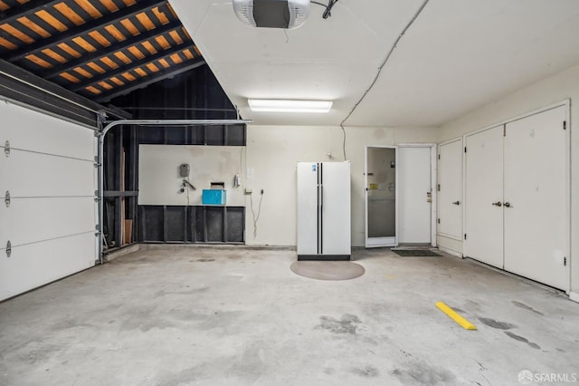 garage with a garage door opener and freestanding refrigerator