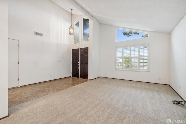 unfurnished room featuring carpet, visible vents, and high vaulted ceiling