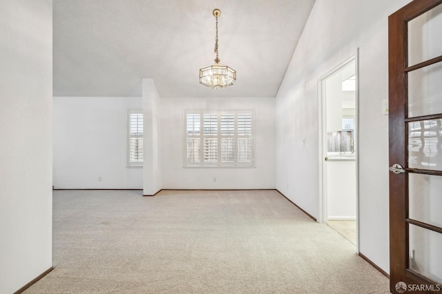 unfurnished room featuring vaulted ceiling, baseboards, an inviting chandelier, and carpet floors