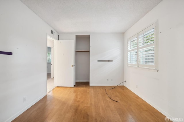 empty room featuring a textured ceiling, a healthy amount of sunlight, and wood finished floors