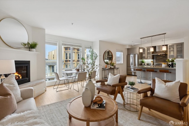 living room featuring light wood-style floors, a glass covered fireplace, and track lighting