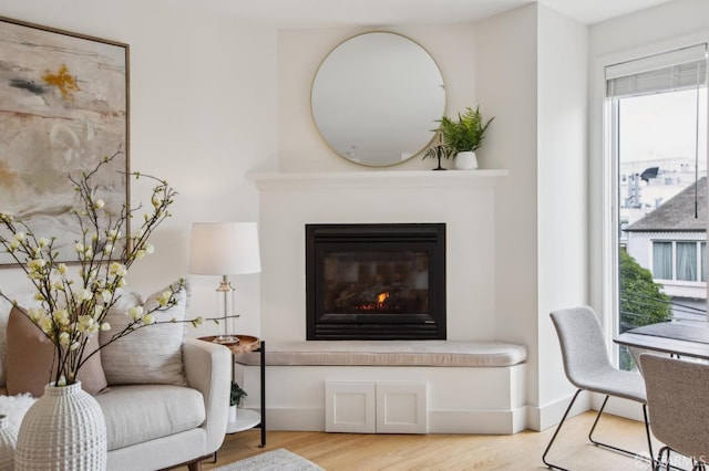 living room featuring baseboards, a glass covered fireplace, and light wood finished floors