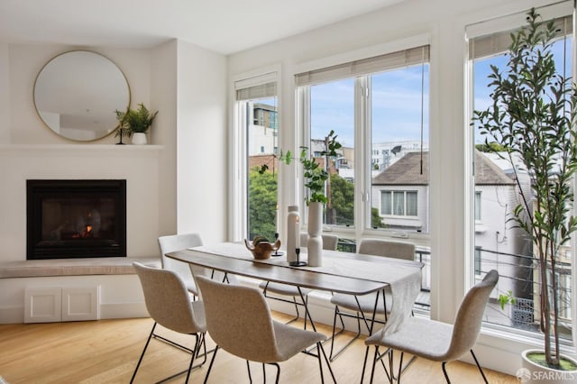 dining room featuring light wood-type flooring and a glass covered fireplace