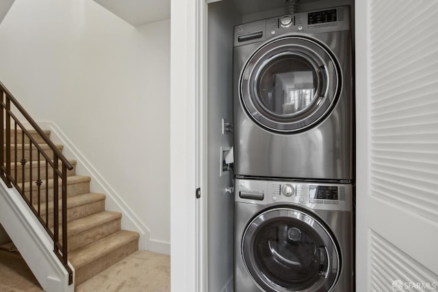 washroom featuring laundry area, stacked washer / dryer, and carpet