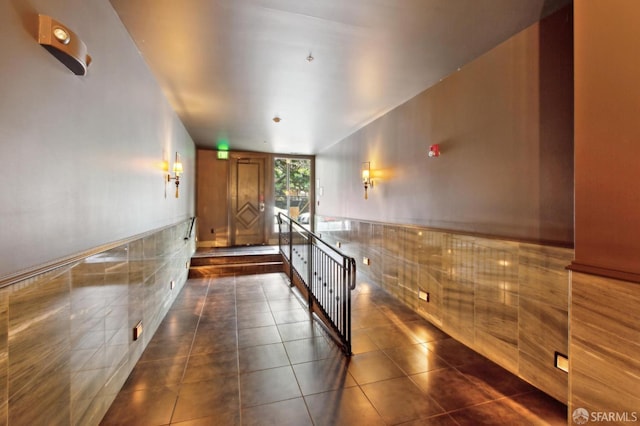 kitchen with wainscoting, brown cabinets, dark tile patterned flooring, and tile walls