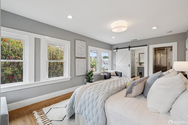 4145 Emerald St, Oakland, CA 94609 - bedroom with a barn door, wood finished floors, radiator heating unit, recessed lighting, and ensuite bathroom