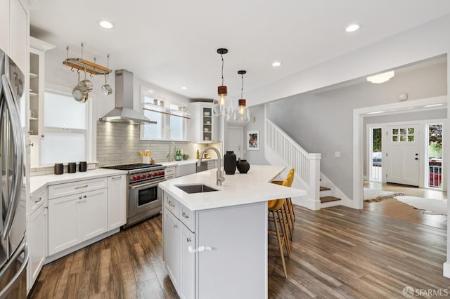 4145 Emerald St, Oakland, CA 94609 - kitchen with stainless steel appliances, wall chimney range hood, dark wood-type flooring, a breakfast bar, and decorative backsplash
