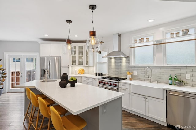 4145 Emerald St, Oakland, CA 94609 - kitchen featuring stainless steel appliances, wall chimney exhaust hood, a breakfast bar, tasteful backsplash, and white cabinets