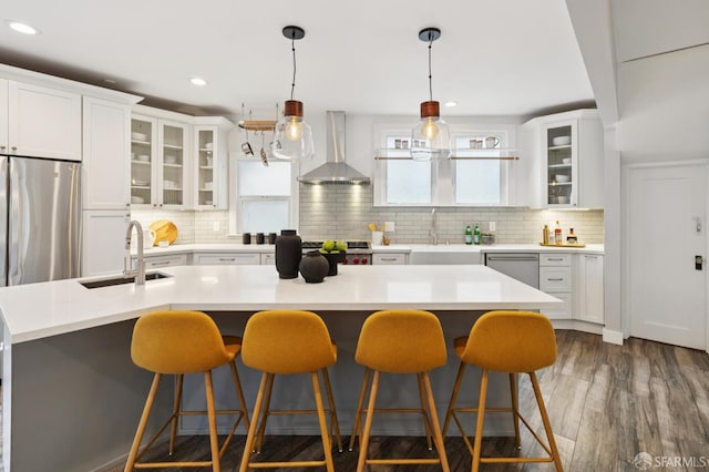 4145 Emerald St, Oakland, CA 94609 - kitchen featuring wall chimney exhaust hood, appliances with stainless steel finishes, a kitchen breakfast bar, backsplash, and recessed lighting