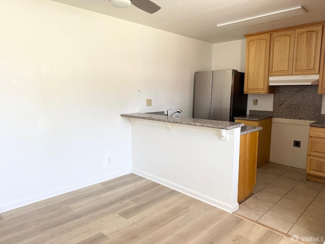 1200 Lemontree Way Unit 1, Antioch, CA 94509 - kitchen featuring under cabinet range hood, freestanding refrigerator, a kitchen breakfast bar, a peninsula, and stone countertops