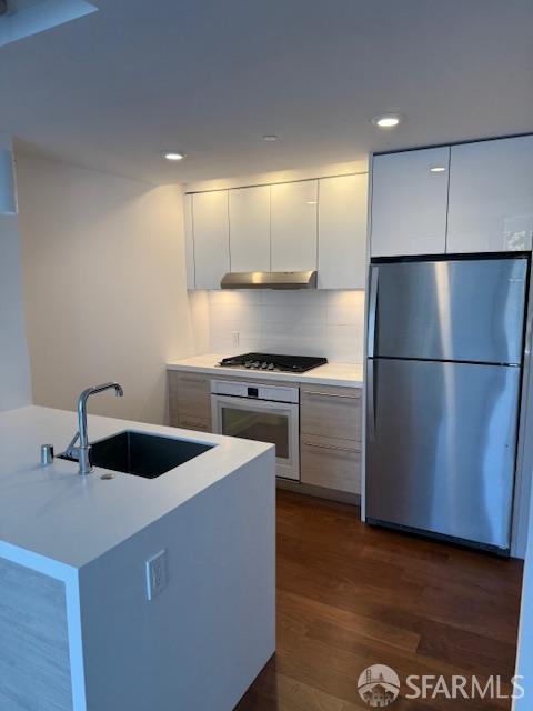 555 Fulton St Unit 322, San Francisco, CA 94102 - kitchen with appliances with stainless steel finishes, modern cabinets, light countertops, backsplash, and dark wood-style floors