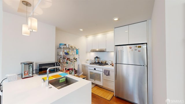 555 Fulton St Unit 322, San Francisco, CA 94102 - kitchen featuring appliances with stainless steel finishes, under cabinet range hood, light countertops, white cabinetry, and decorative light fixtures