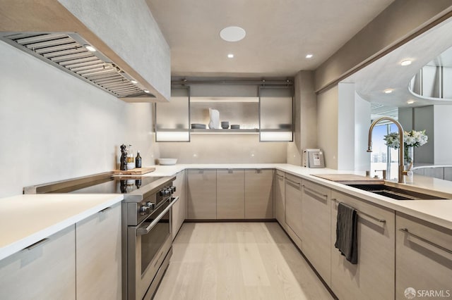 kitchen featuring high end stove, sink, range hood, and light hardwood / wood-style flooring