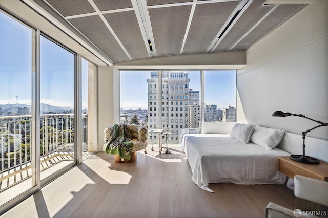 bedroom featuring access to exterior, hardwood / wood-style floors, and expansive windows