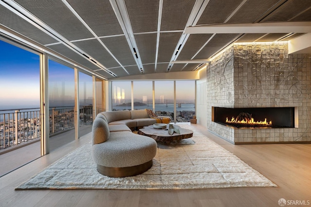 interior space featuring a water view, a fireplace, expansive windows, and hardwood / wood-style flooring