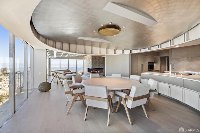 dining space with sink, a fireplace, and hardwood / wood-style flooring