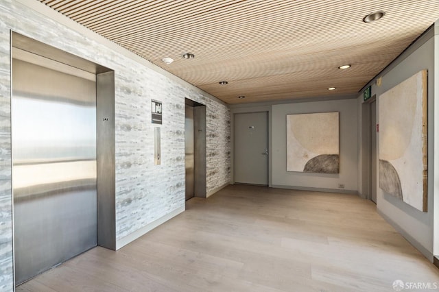 corridor featuring elevator and light hardwood / wood-style flooring