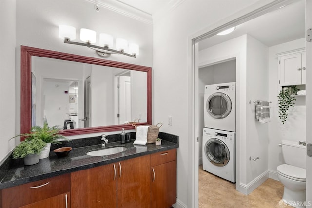 bathroom featuring stacked washer / drying machine, toilet, tile patterned flooring, crown molding, and vanity