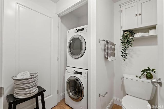 laundry room featuring stacked washer / drying machine and light tile patterned flooring