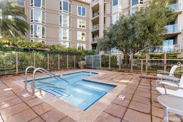 view of pool featuring fence and a community hot tub