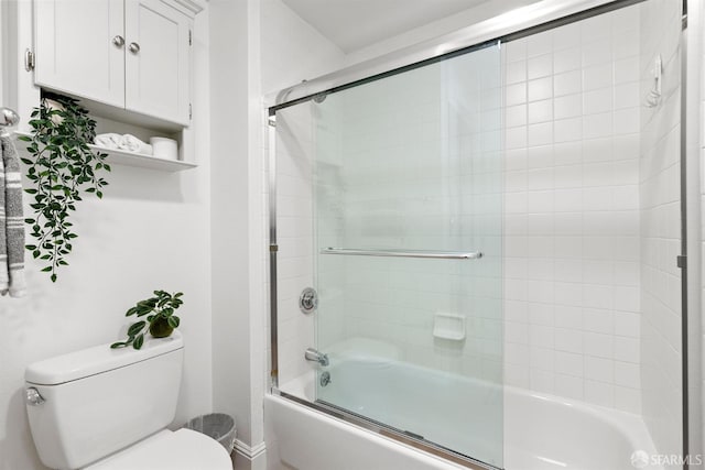 bathroom featuring baseboards, combined bath / shower with glass door, and toilet