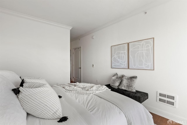 bedroom with baseboards, ornamental molding, wood finished floors, and visible vents