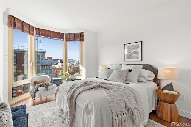 bedroom featuring crown molding, baseboards, wood finished floors, and access to exterior