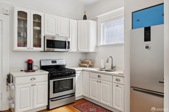 1932 Fell St Unit 1, San Francisco, CA 94117 - kitchen featuring appliances with stainless steel finishes, a sink, white cabinets, glass insert cabinets, and light countertops