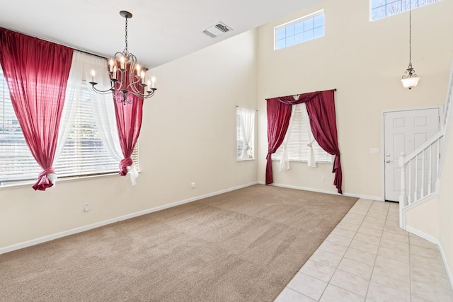 tiled empty room featuring a towering ceiling and a chandelier