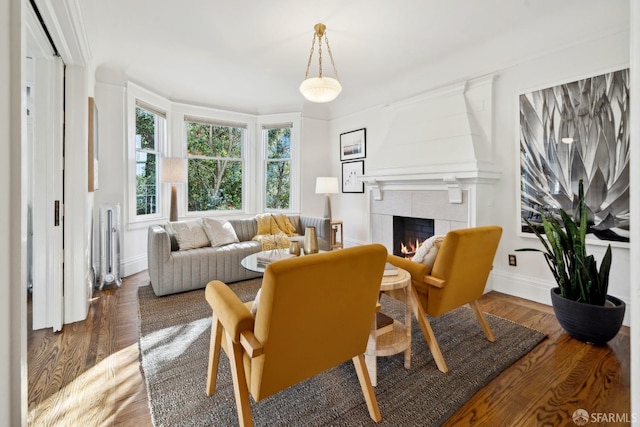 living room featuring ornamental molding, a tile fireplace, and dark hardwood / wood-style floors